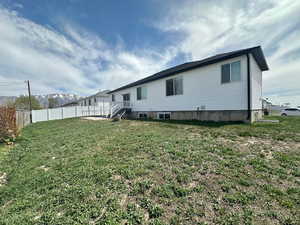 Back of house featuring a yard, a mountain view, and fence