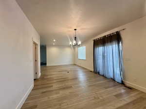 Unfurnished dining area with baseboards, light wood finished floors, and an inviting chandelier