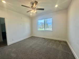Spare room with dark carpet, ceiling fan, and baseboards