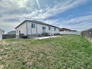 Rear view of property with a fenced backyard, a patio, and a lawn