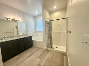 Full bathroom featuring a bath, curtained shower, a sink, double vanity, and wood finished floors