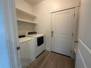 Clothes washing area with light wood-type flooring, washing machine and dryer, and laundry area