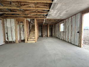 Miscellaneous room with unfinished concrete flooring and stairs