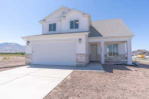 View of front of home with stone siding, concrete driveway, a porch, a mountain view, and an attached garage