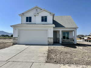 View of front of home with concrete driveway, a garage, stone siding, and a porch