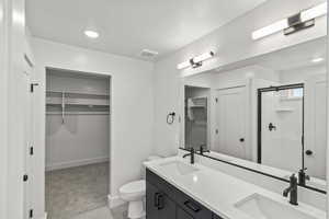 Bathroom with toilet, a stall shower, a sink, and baseboards