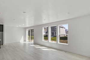 Unfurnished living room featuring visible vents, a wealth of natural light, and light wood-type flooring