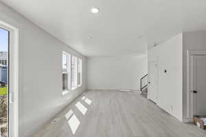 Unfurnished living room featuring visible vents, light wood-type flooring, stairs, and recessed lighting