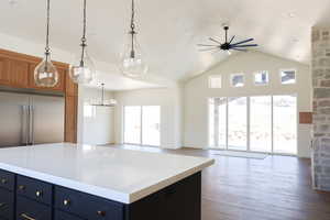 Kitchen with ceiling fan with notable chandelier, open floor plan, wood finished floors, and brown cabinetry