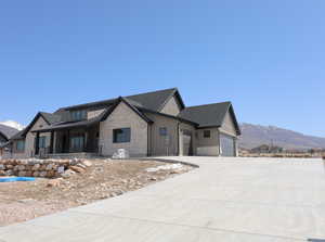 View of front of home featuring an attached garage, board and batten siding, a mountain view, and concrete driveway