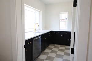 Kitchen with light floors, light countertops, dishwasher, dark cabinetry, and a sink