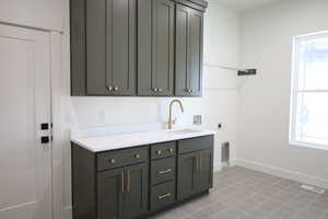 Clothes washing area featuring a sink, visible vents, washer hookup, cabinet space, and electric dryer hookup