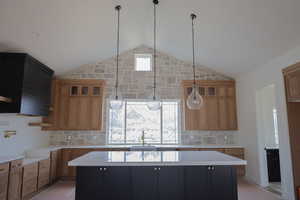 Kitchen featuring a sink, light countertops, a kitchen island, and lofted ceiling