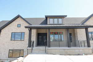 Doorway to property with roof with shingles, covered porch, and stone siding