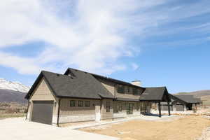 View of front of house with board and batten siding, a mountain view, driveway, and a chimney