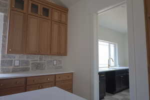 Kitchen with tasteful backsplash, brown cabinets, light countertops, and a sink