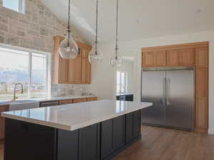 Kitchen featuring light countertops, vaulted ceiling, a sink, a center island, and appliances with stainless steel finishes