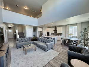Living area with visible vents, recessed lighting, a towering ceiling, stairs, and light wood-style flooring