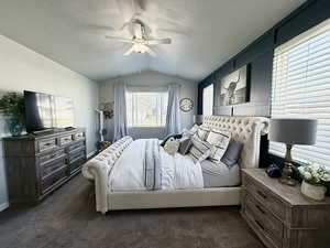 Bedroom with ceiling fan, a textured ceiling, dark colored carpet, and lofted ceiling