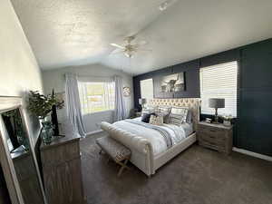 Bedroom with dark carpet, a textured ceiling, baseboards, and lofted ceiling