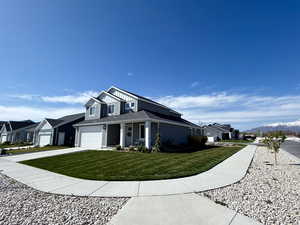 View of front facade featuring a mountain view, an attached garage, a front lawn, a residential view, and driveway