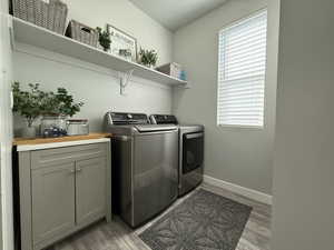 Laundry area featuring plenty of natural light, light wood finished floors, independent washer and dryer, and baseboards