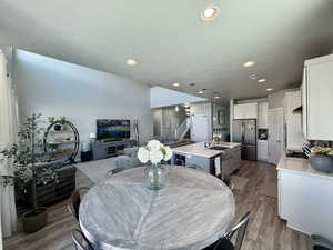 Dining space featuring dark wood-style flooring, stairway, recessed lighting, and a textured ceiling