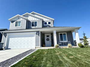 Traditional-style house with concrete driveway, board and batten siding, a front yard, a porch, and a garage