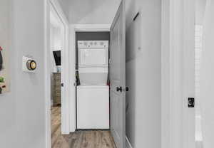 Washroom featuring light wood-style flooring, stacked washer and dryer, and laundry area