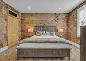 Bedroom with light wood-type flooring, brick wall, baseboards, and recessed lighting