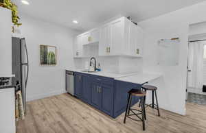Kitchen featuring a sink, baseboards, blue cabinets, and stainless steel appliances