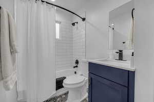 Bathroom featuring toilet, vanity, and shower / bath combination with curtain