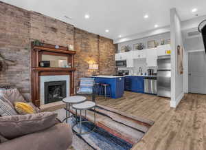 Living room with light wood-type flooring, a fireplace, visible vents, and recessed lighting
