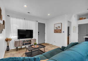 Living area featuring wood finished floors, baseboards, visible vents, and recessed lighting
