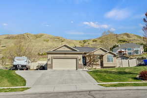 Ranch-style home with a mountain view, driveway, an attached garage, a front lawn, and fence