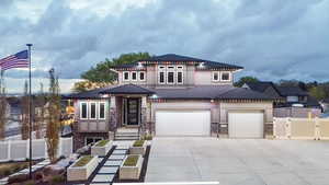View of front of property featuring stone siding, driveway, fence, and a garage