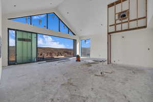 Unfurnished living room featuring a mountain view, a healthy amount of sunlight, and high vaulted ceiling