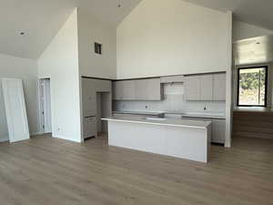 Kitchen featuring high vaulted ceiling, light wood-type flooring, and a center island