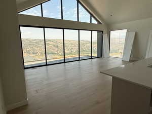 Unfurnished living room with high vaulted ceiling, wood finished floors, and a mountain view