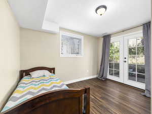 Bedroom featuring baseboards, multiple windows, dark wood-style floors, french doors, and access to outside