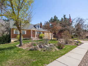 View of front of house with a front yard, brick siding, and a chimney