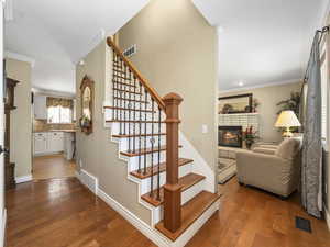 Stairway with baseboards, a brick fireplace, hardwood / wood-style flooring, and ornamental molding