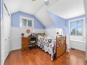 Bedroom with a ceiling fan, hardwood / wood-style floors, wainscoting, and visible vents