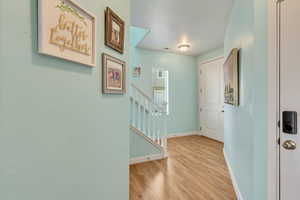 Entryway with visible vents, baseboards, light wood-style floors, and stairs