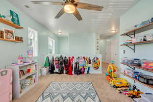 Rec room with carpet flooring, a ceiling fan, and visible vents