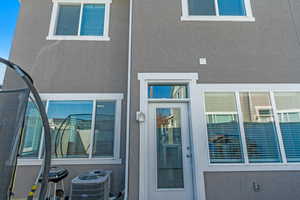 Entrance to property with stucco siding and central air condition unit