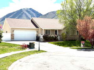 Ranch-style home with concrete driveway, an attached garage, a mountain view, and stucco siding