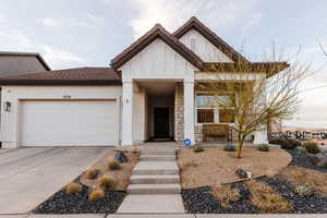 View of front of property with a garage, driveway, board and batten siding, and a tile roof