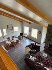 Tiled living area with a stone fireplace, a textured ceiling, and beam ceiling