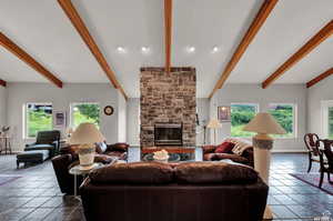 Living room featuring a fireplace, baseboards, beam ceiling, and dark tile patterned flooring